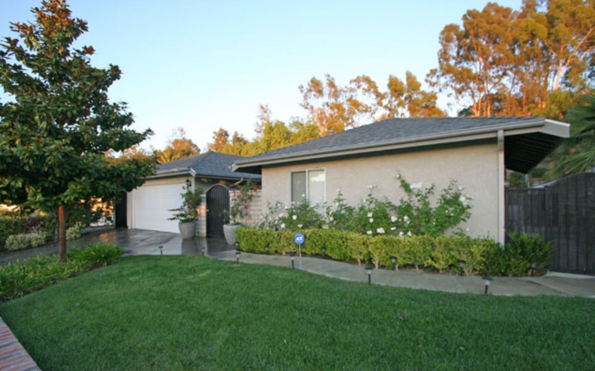 A suburban house with a well-maintained garden and lawn in the foreground.