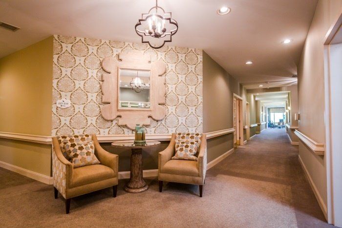 A well-decorated hallway featuring two chairs, a small table, and a mirror on the wall.