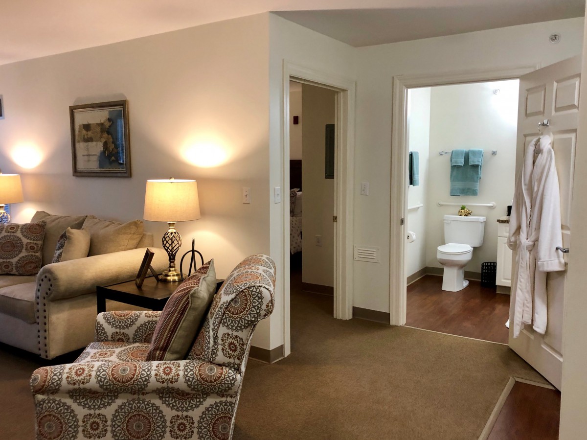 A cozy living room with a view into a bathroom through an open door.