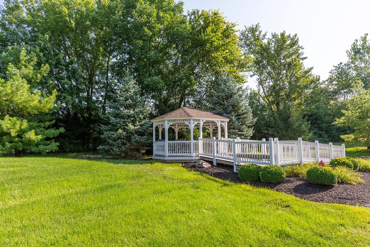 A beautiful gazebo surrounded by lush greenery and a well-maintained lawn.