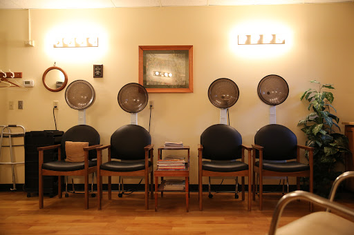 A cozy salon waiting area with comfortable chairs and vintage hair dryers.