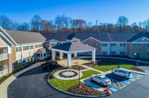 Aerial view of a residential building with a driveway and parked cars.