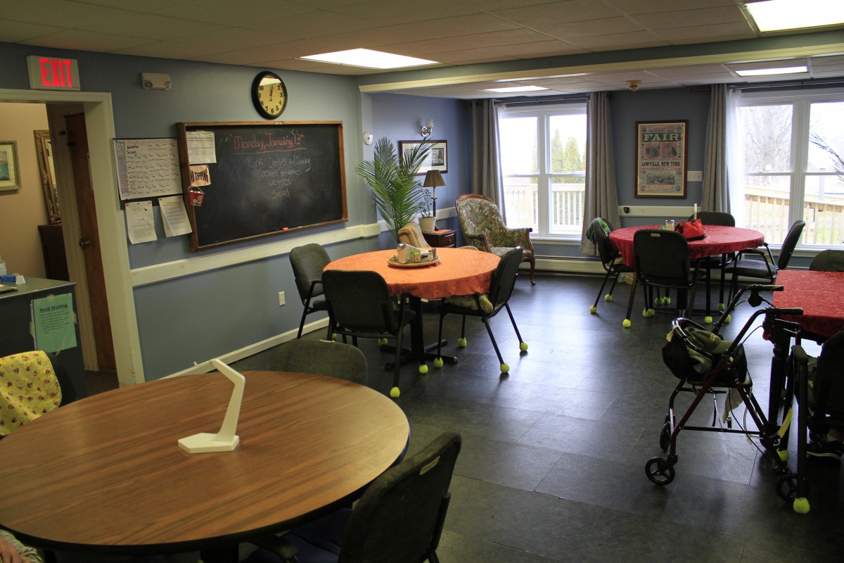 A cozy room with tables, chairs, and a chalkboard on the wall.