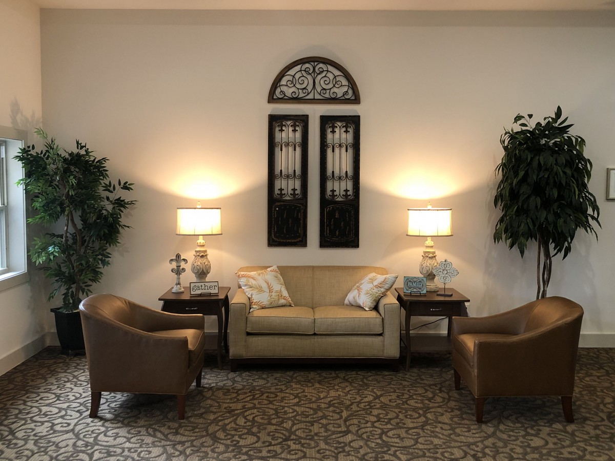 A cozy living room setup with a sofa, two chairs, lamps, and decorative plants.
