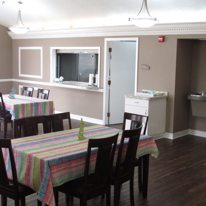 A dining area with tables and chairs, each covered with colorful tablecloths.