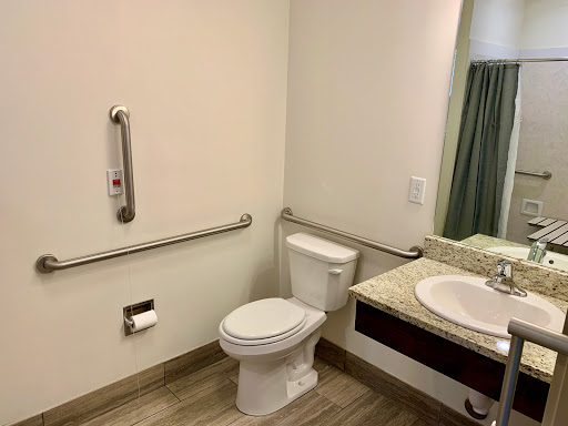 A clean and accessible bathroom featuring a toilet, sink, and grab bars for support.