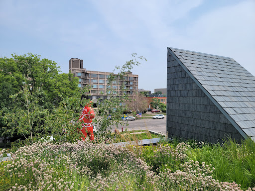 A vibrant urban scene featuring a person in bright attire among lush greenery and modern architecture.