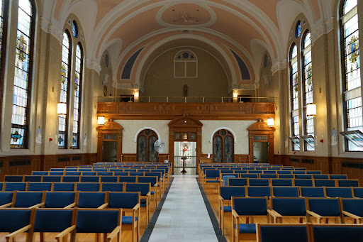 A serene interior view of a church with rows of blue chairs and elegant architecture.