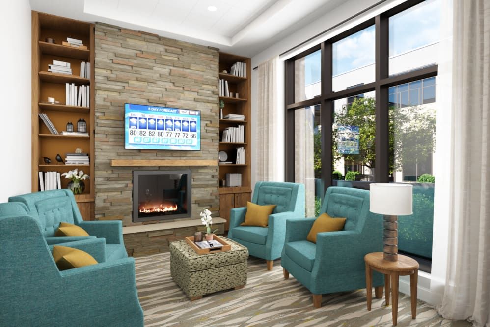 A modern living room featuring a stone fireplace, cozy armchairs, and large windows that invite natural light.