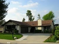 A suburban house with a driveway and surrounding greenery.