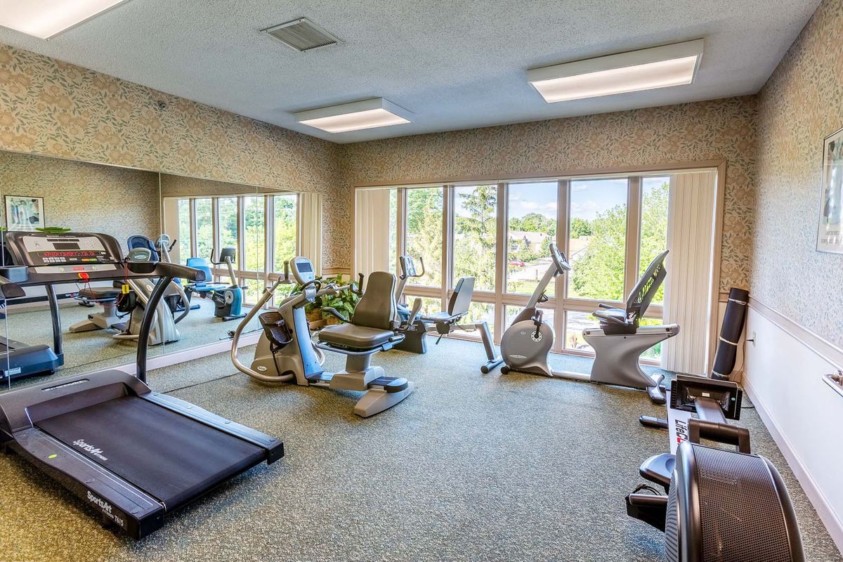 A well-lit gym with various exercise equipment including treadmills and stationary bikes.