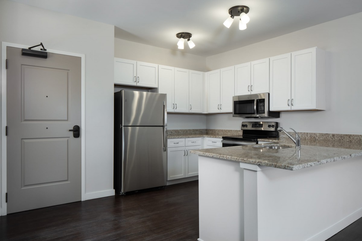 A modern kitchen with white cabinets and stainless steel appliances.