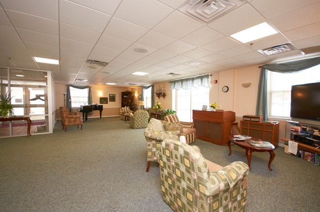 A spacious living room with multiple seating areas and a piano, decorated in neutral tones.
