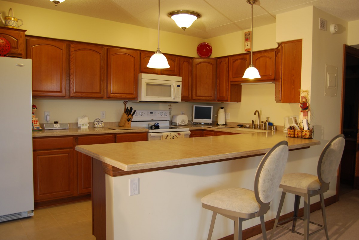 A cozy kitchen with wooden cabinets and a central island with seating.