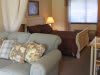 A cozy living space with a comfy sofa, decorative cushions, and a bed in the background.