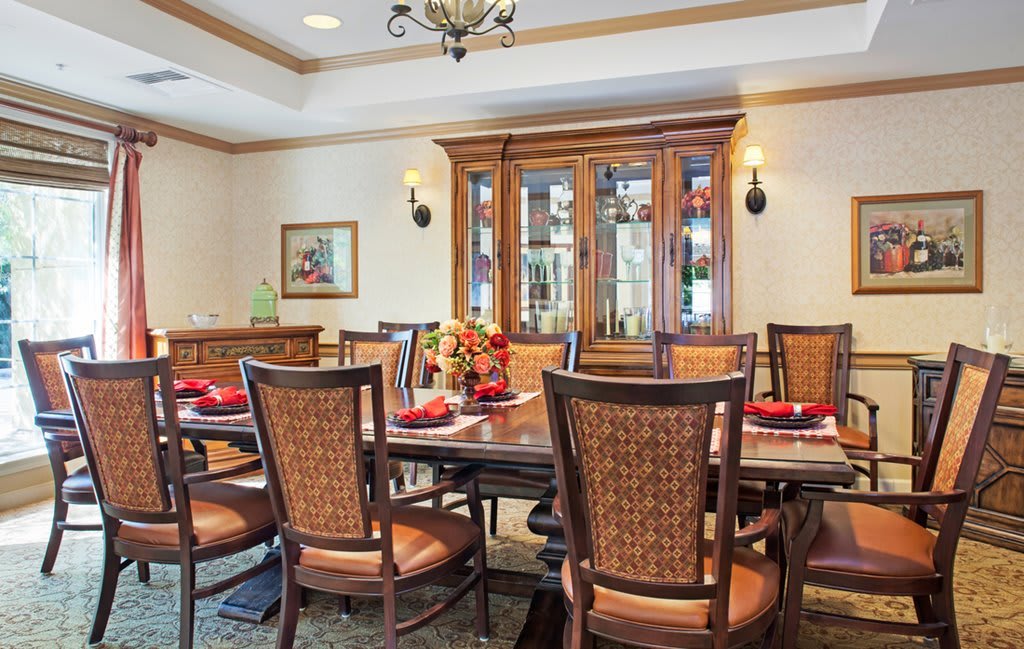 A beautifully designed dining room with a large table, chairs, and an elegant cabinet in the background.