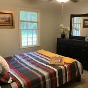 Cozy bedroom with striped bedding and a dresser with mirror.