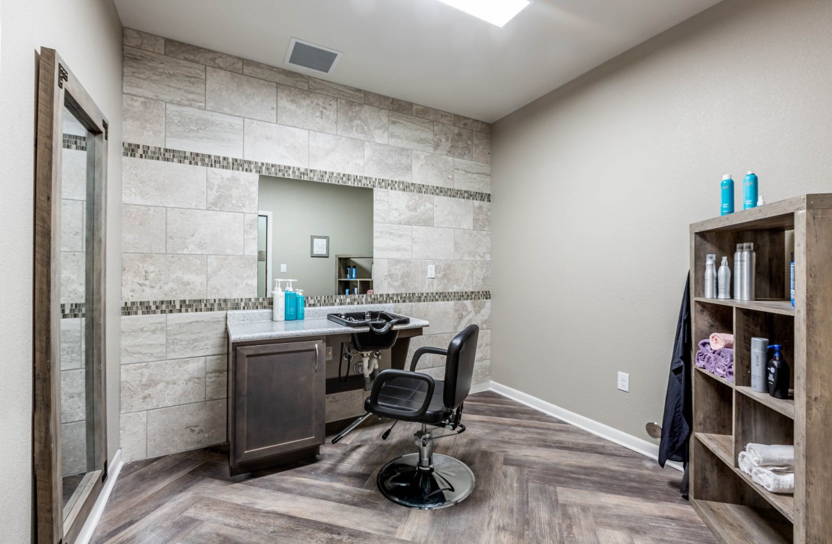A modern barber shop interior featuring a styling station with a mirror and chair.