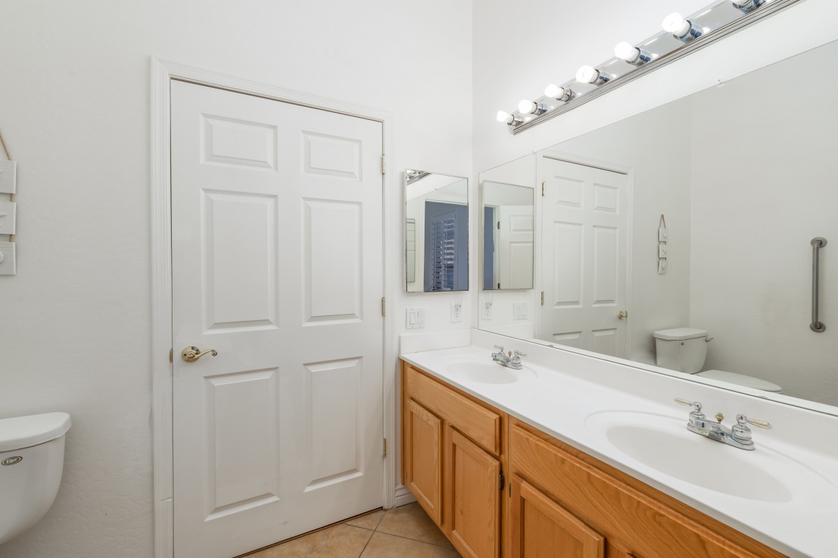 A clean and bright bathroom with a double sink vanity, large mirrors, and overhead lighting.
