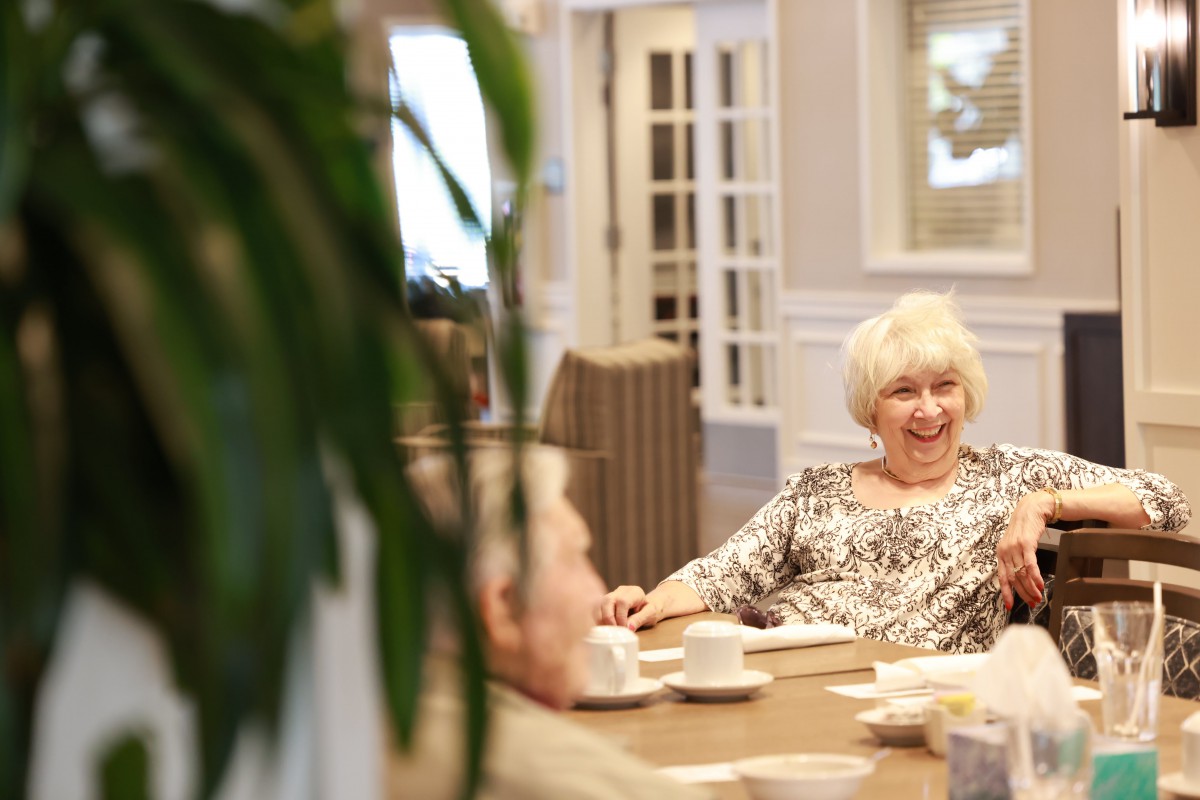 A group of seniors enjoying a conversation over coffee indoors.