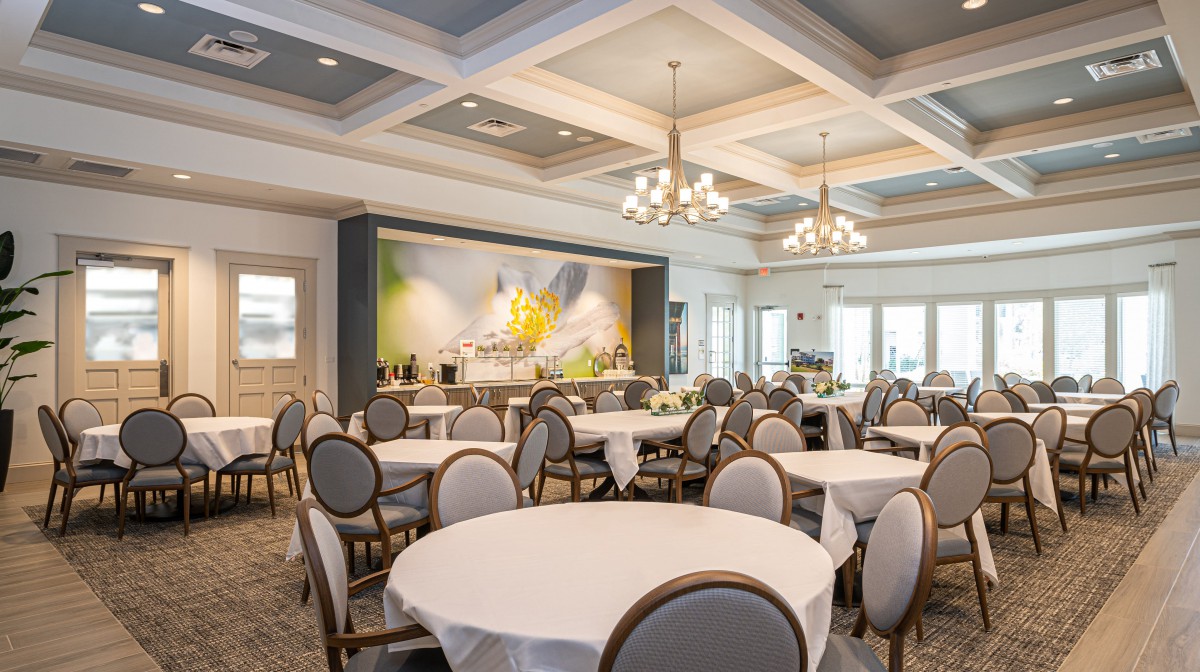 An elegant banquet hall with round tables and chandeliers, set up for an event.