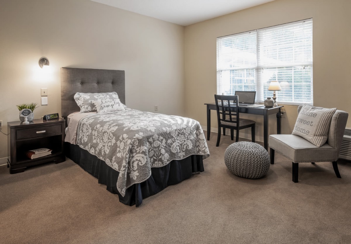 A cozy bedroom with a single bed, desk, and window allowing natural light.