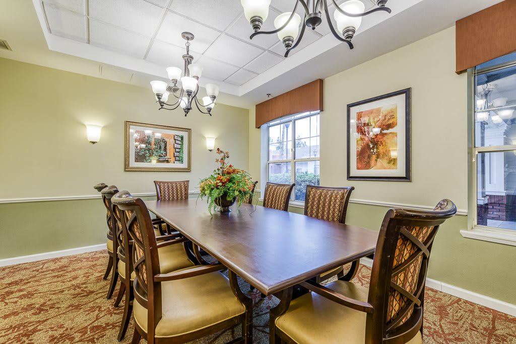 A well-decorated dining room with a large conference table, elegant chairs, and soft lighting.