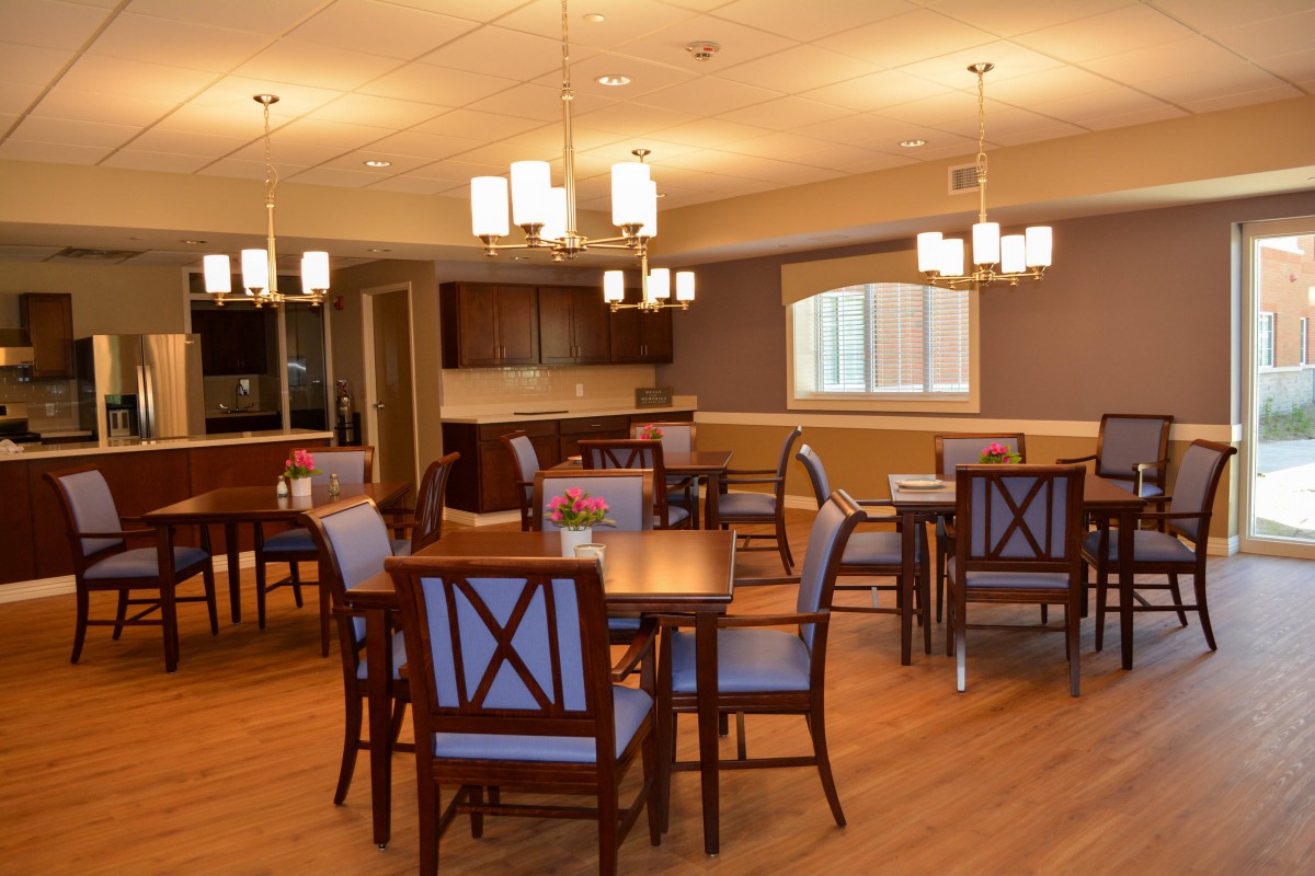 A cozy dining area with wooden tables and chairs, soft lighting, and a warm ambiance.
