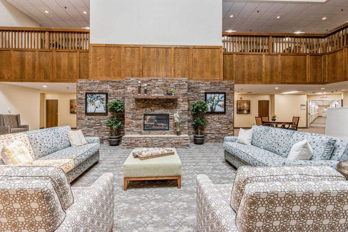 A spacious lobby featuring a cozy seating area with sofas and a central stone fireplace.