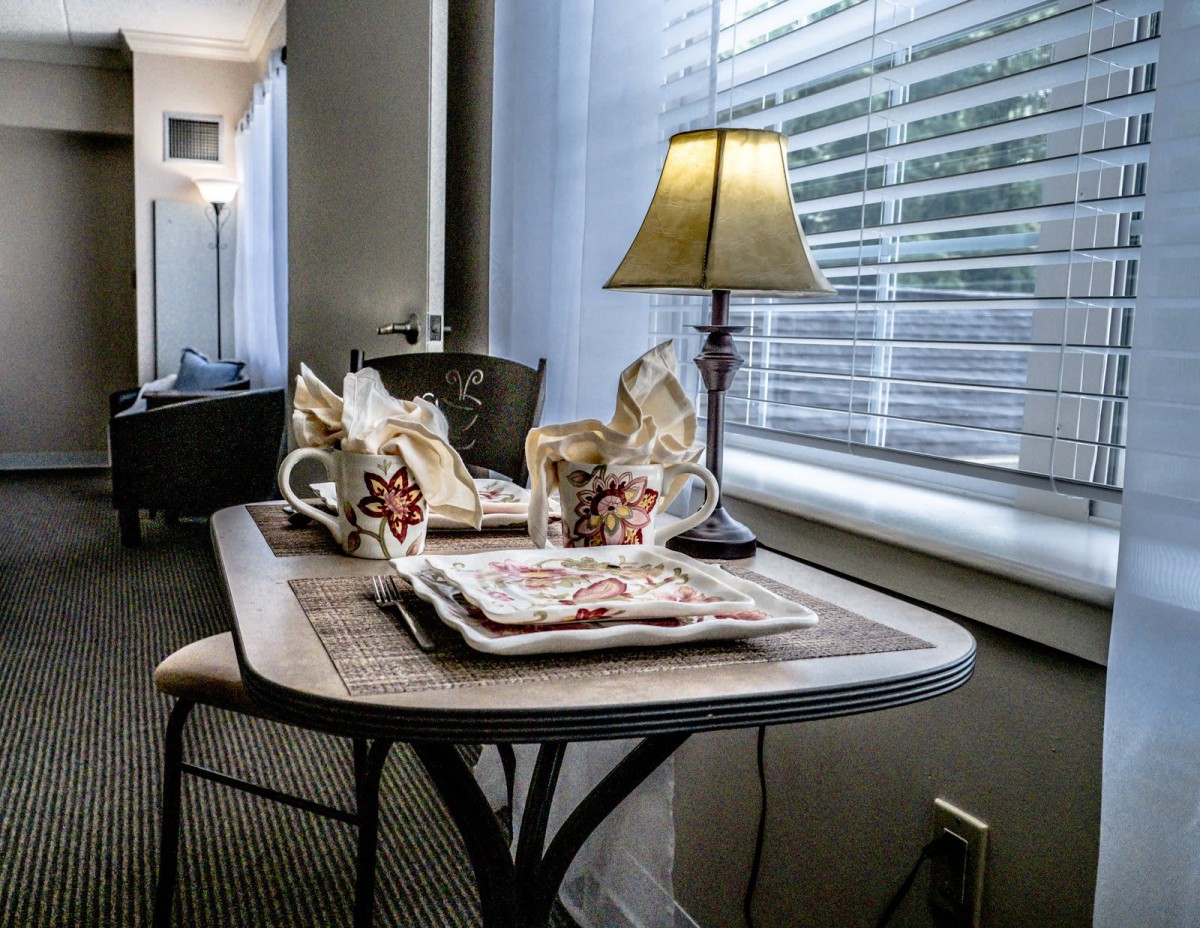 Cozy interior table setting with a lamp, cups, and napkins by the window.