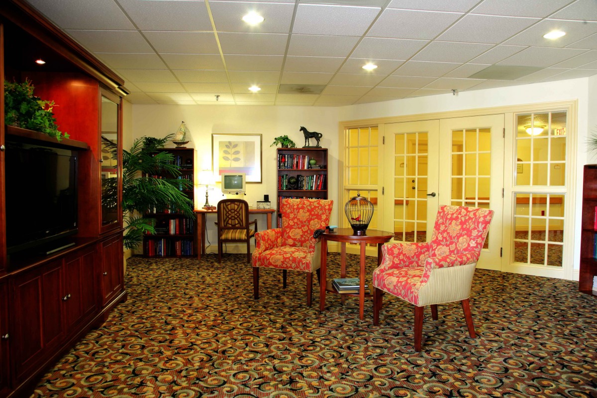 A cozy office waiting room with patterned chairs, bookshelves, and a carpeted floor.