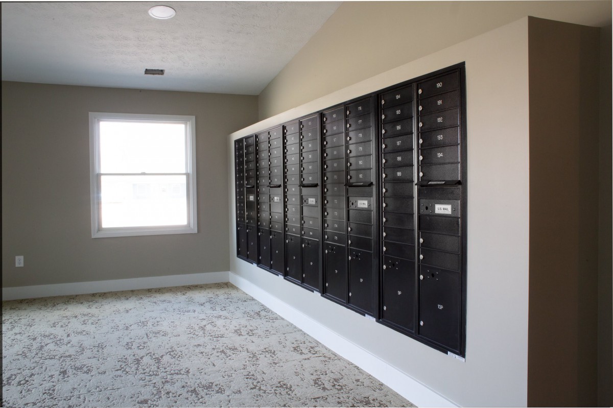 A mailroom with a wall of black mailboxes in an apartment building.
