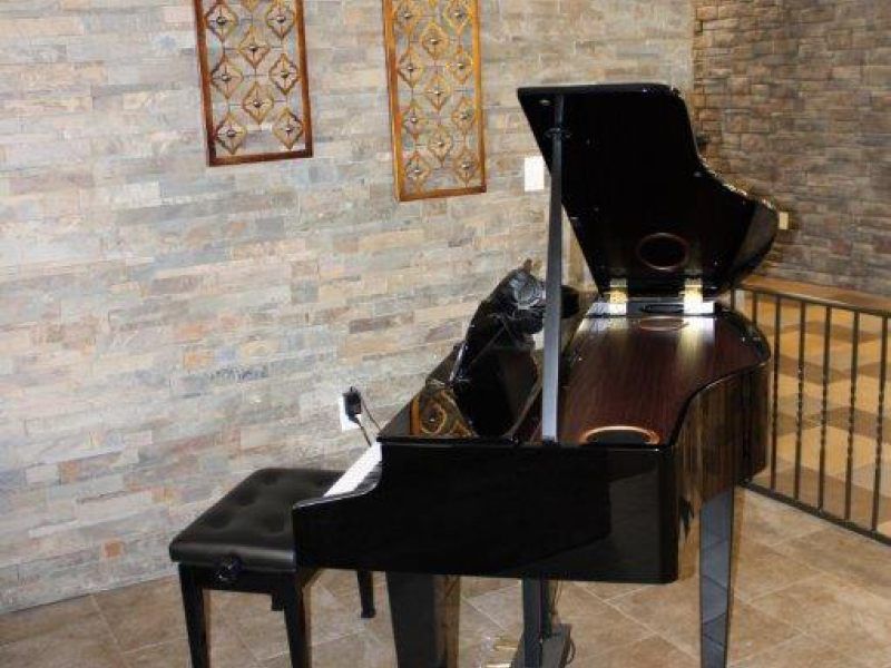 A grand piano in a beautifully decorated interior with brick walls.