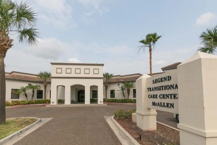 Entrance to the Legend Transitional Care Center with palm trees lining the path.