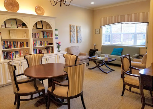 A cozy living room setting featuring a round dining table, stylish chairs, and a bookshelf filled with books.