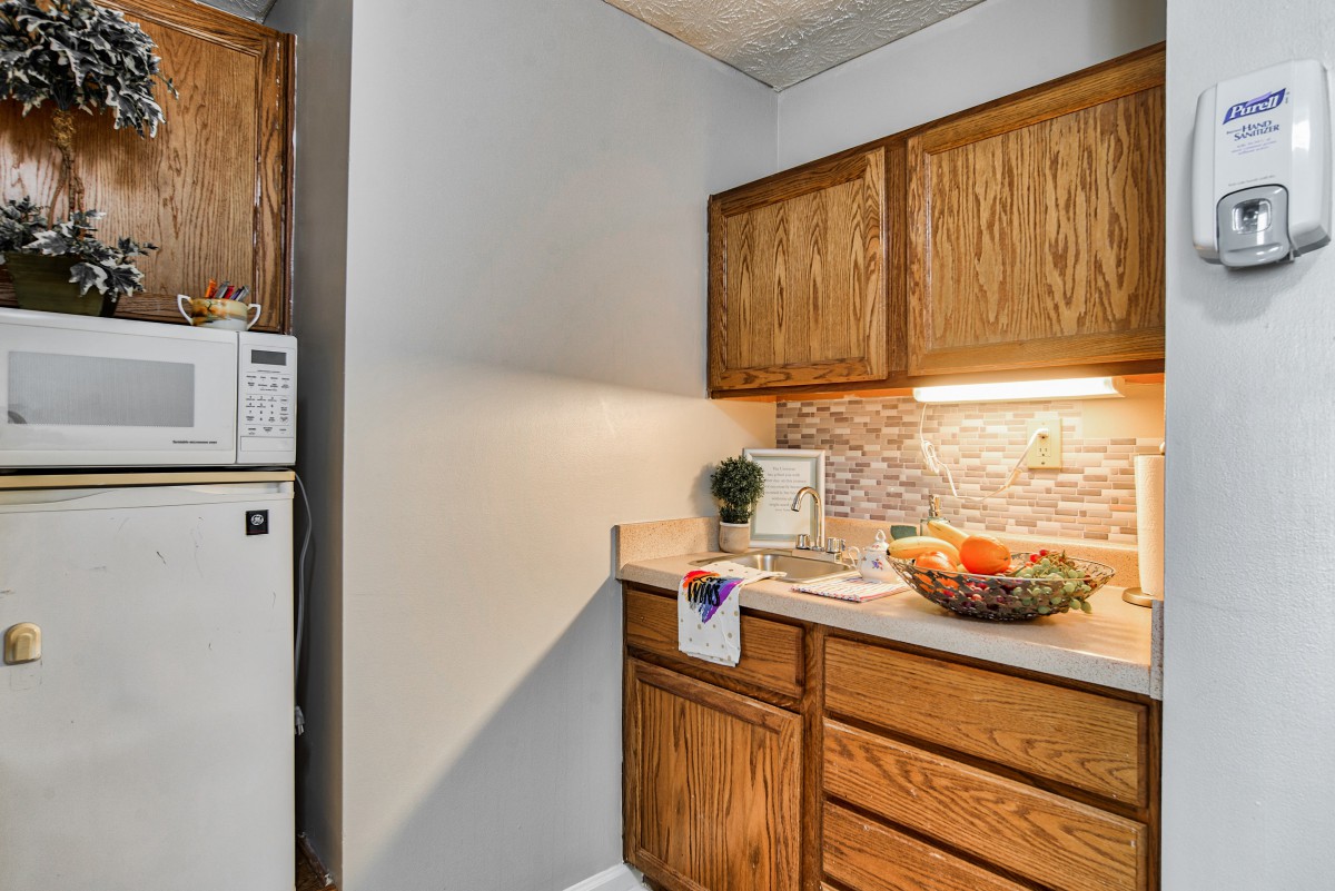 A cozy kitchen corner with wooden cabinets and a countertop featuring a fruit bowl.