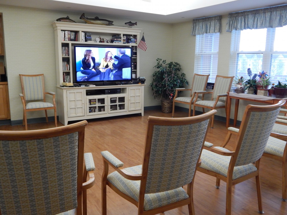 A cozy living room with chairs arranged in front of a large television.