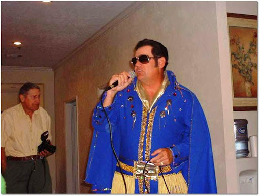 A performer dressed in a blue, embellished costume singing into a microphone.