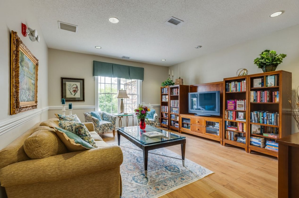 A cozy living room with a sofa, coffee table, and television surrounded by bookshelves.