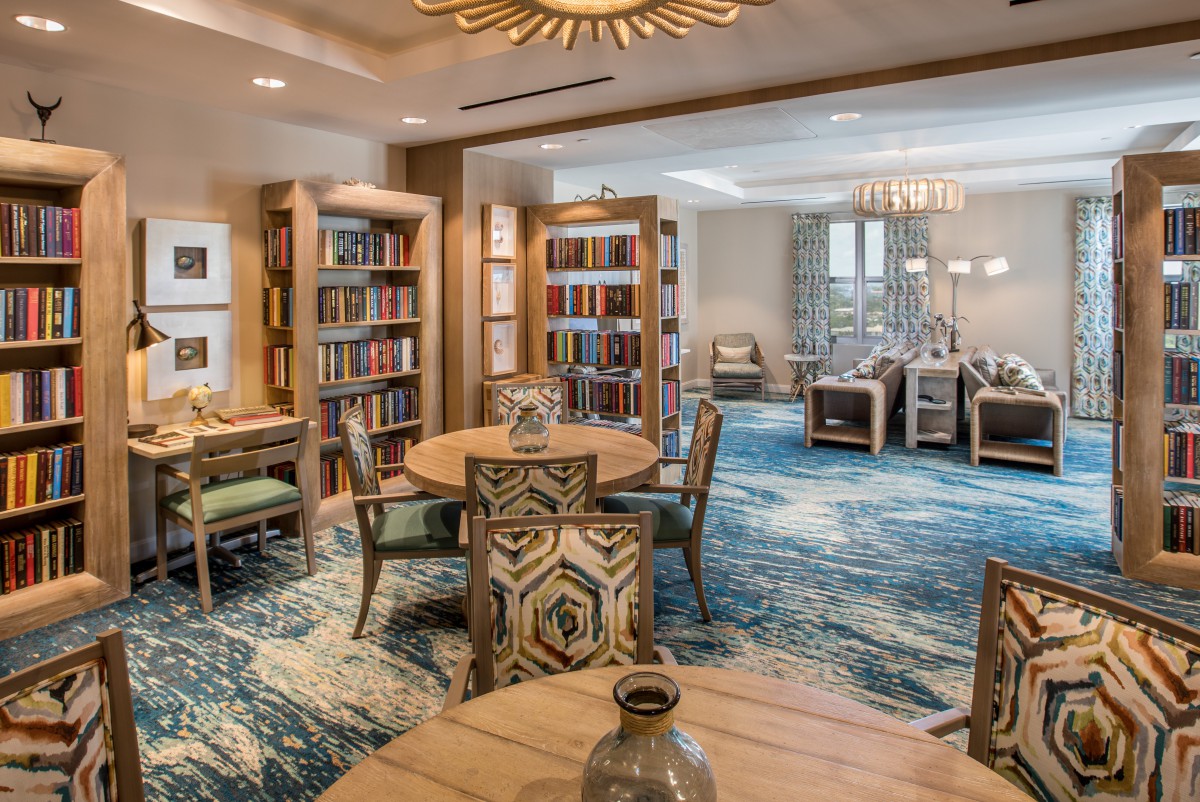 A cozy library with bookshelves, seating areas, and decorative lighting.