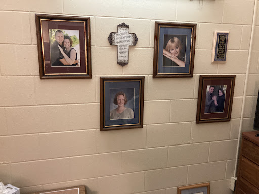 A collection of framed family photographs and a religious cross displayed on a wall.