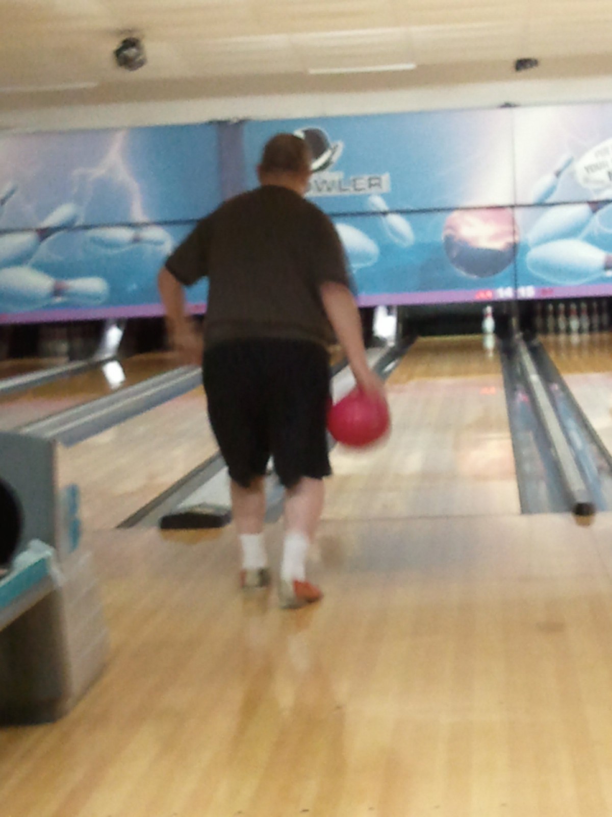 A person bowling at an indoor bowling alley.