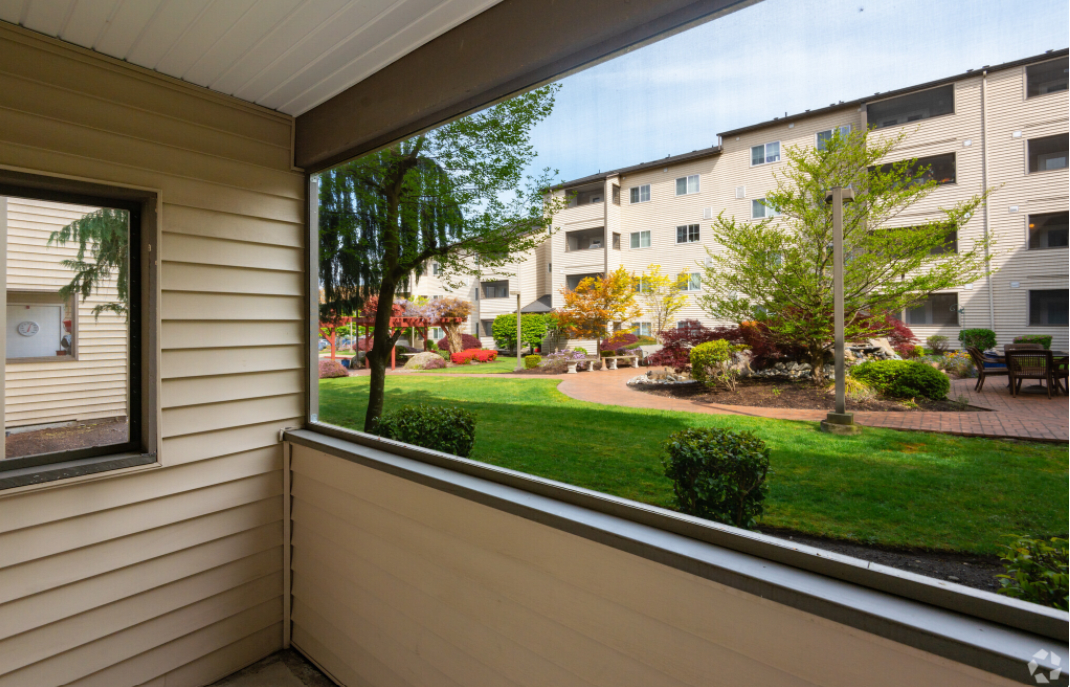 A view from a balcony overlooking a garden and apartment building.