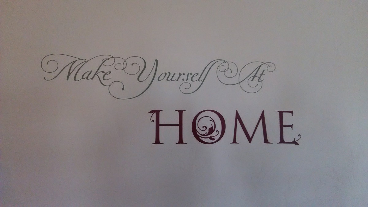 A decorative wall sign with the phrase 'Make Yourself At Home' in elegant calligraphy.