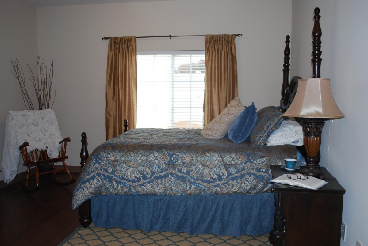 A cozy bedroom with a large bed, decorative pillows, and a window with curtains.