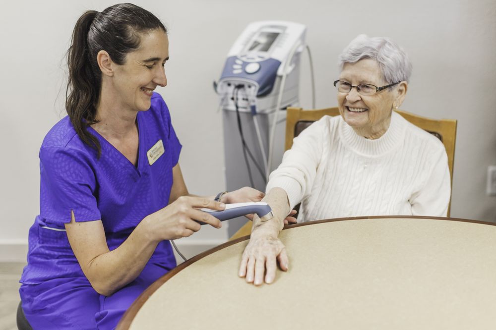 A nurse providing care to an elderly patient using a medical device.