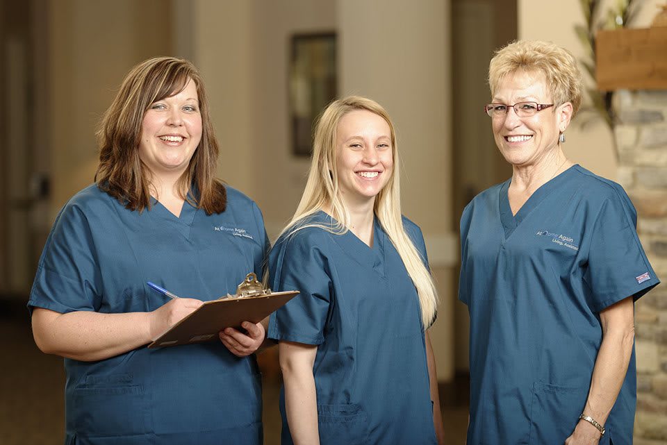 A group of medical professionals in blue scrubs, smiling and standing together.