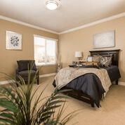 A cozy bedroom with a neatly made bed, decorative pillows, and elegant furnishings.