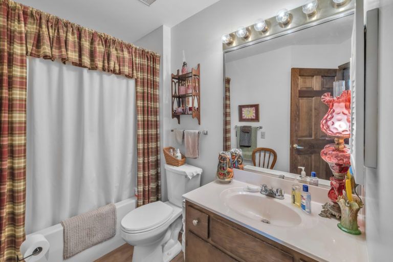 A cozy bathroom with a sink, mirror, and shower curtain, featuring warm decor and vanity lighting.