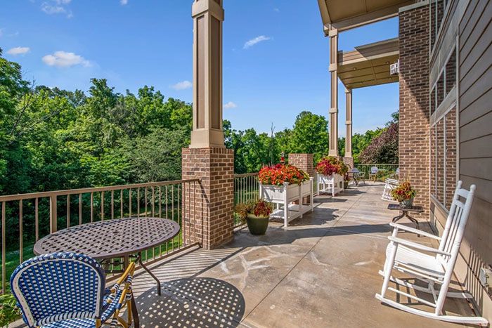 A beautiful outdoor patio featuring tables, chairs, and vibrant plants against a backdrop of lush greenery.